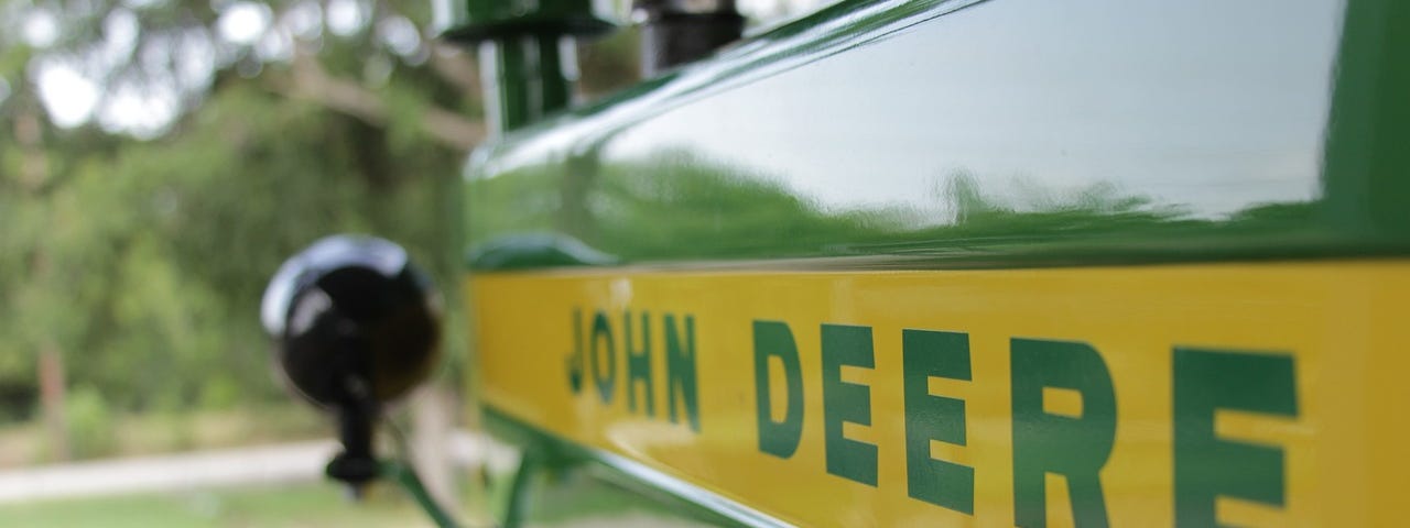IMAGE: The front side of a classic John Deere tractor, showing the signature green and yellow paint and the band with the brand name