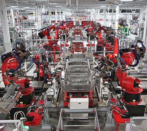 IMAGE: A huge number of red Tesla 3 axis robots in a manufacturing line